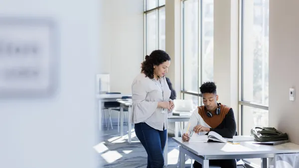 A teacher speaks to a student in a lecture hall.