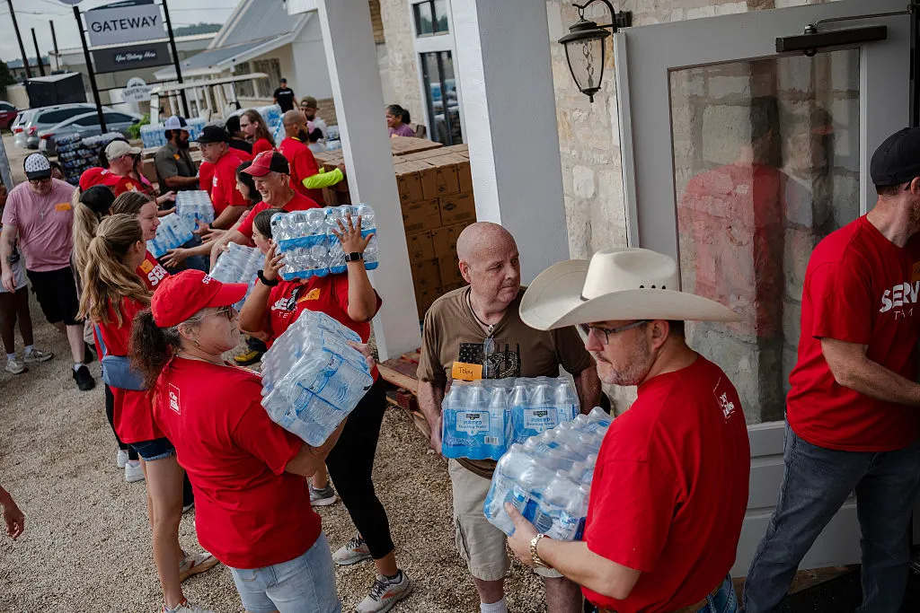 Volunteers carry packs of water bottles to Gateway Kerrville Church in Texas, following a disastrous storm in which water levels surged.