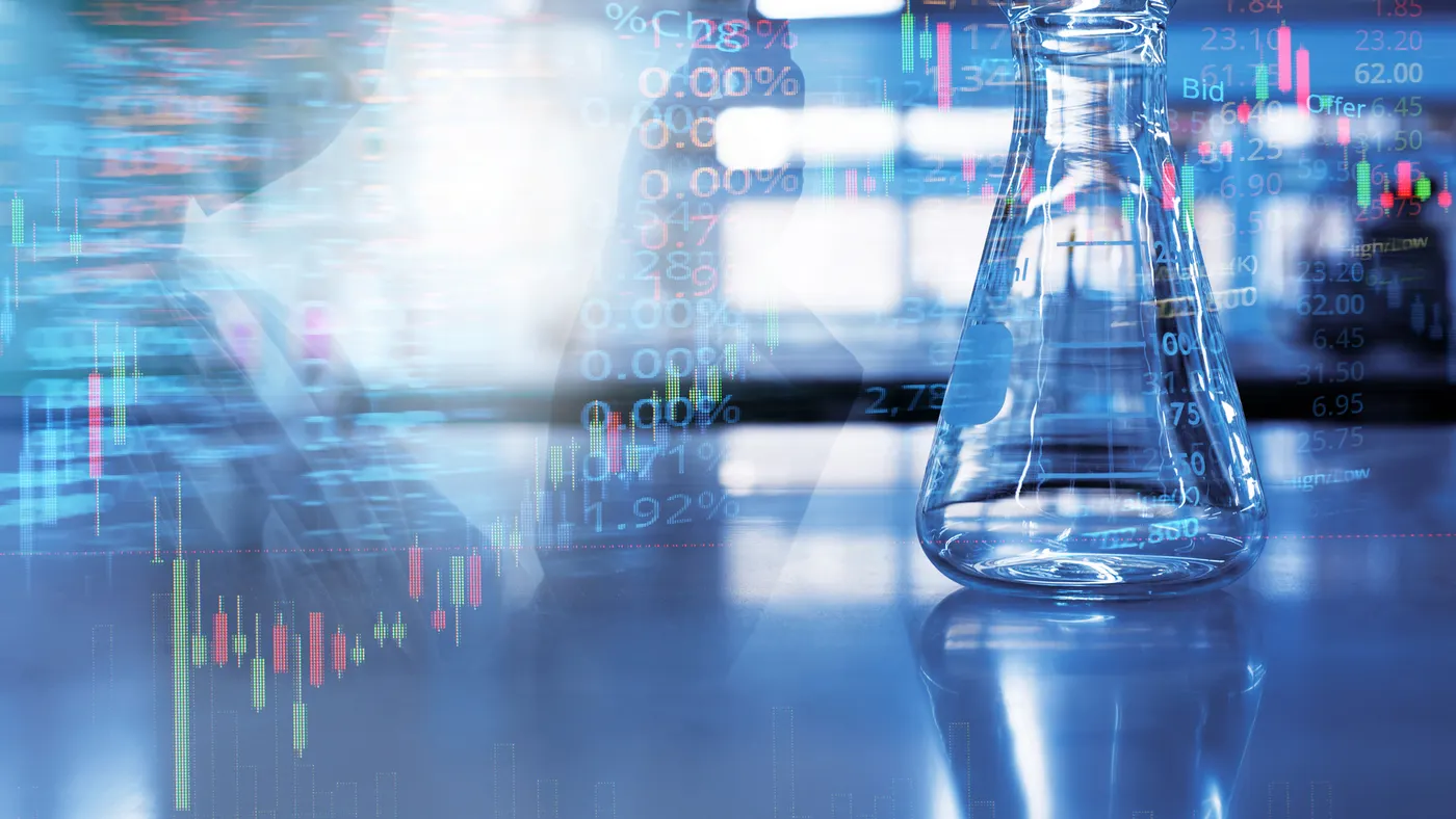 A double exposure image of a glass flask in a laboratory with stock market information in the background.