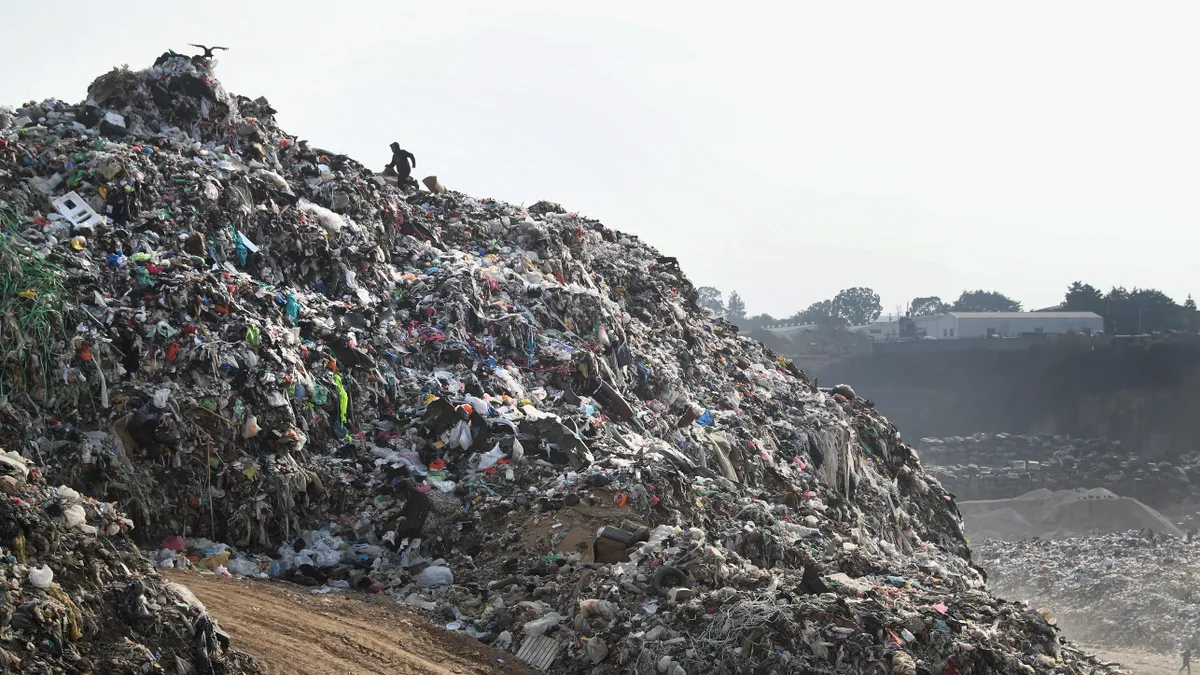 A large open dump, with people scaling the slope, in Guatemala