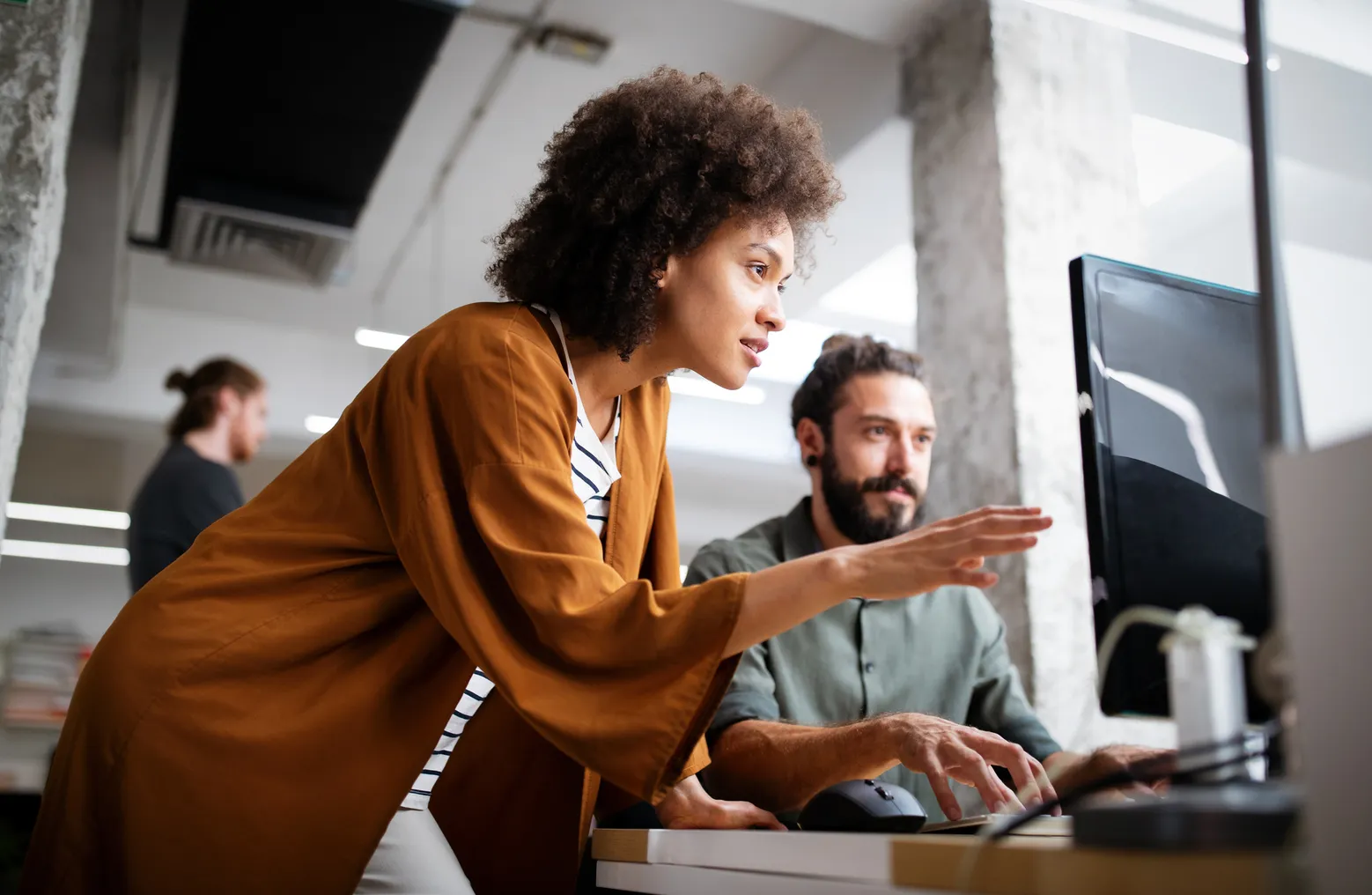 A pair of coworkers look at a computer screen