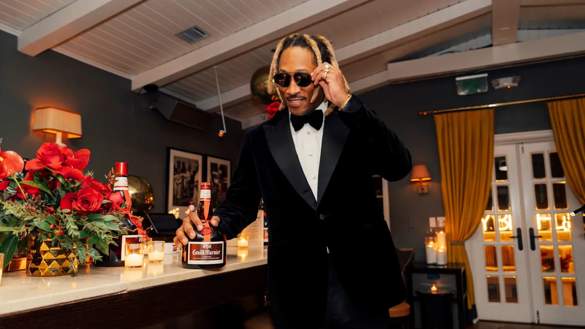 Future wears a black tuxedo while holding a bottle of Grand Marnier.