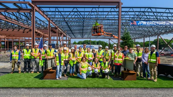 Workers stand in front of completed steel framing for an education facility.