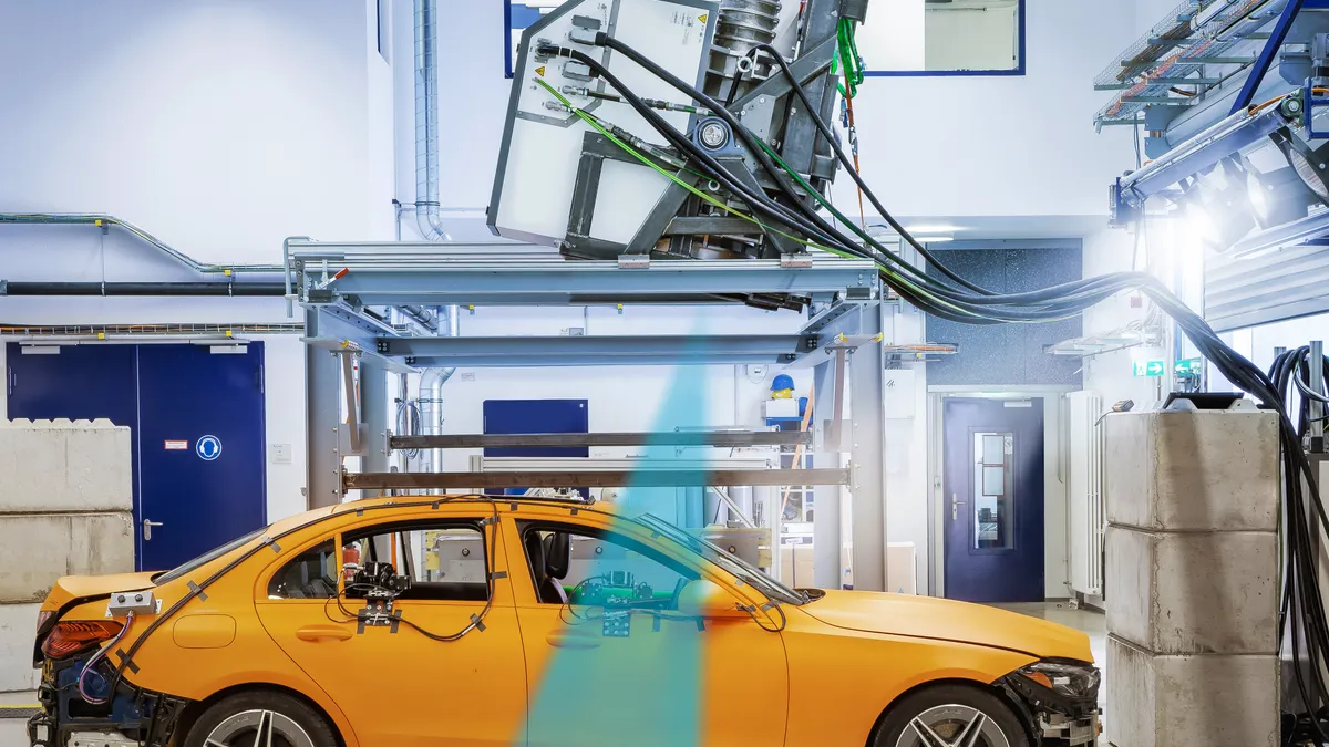 A yellow Mercedes-Benz C Class sedan undergoes crash testing.