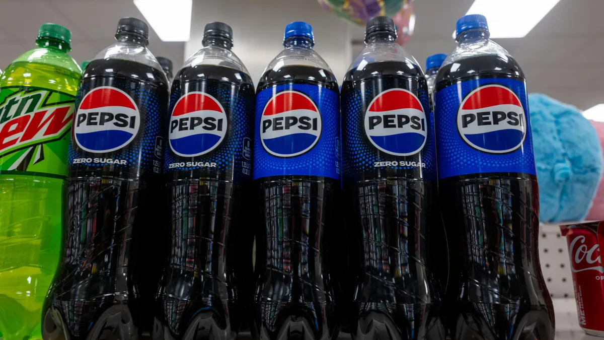 bottles of Pepsi and Mountain Dew are next to each other on a store shelf.
