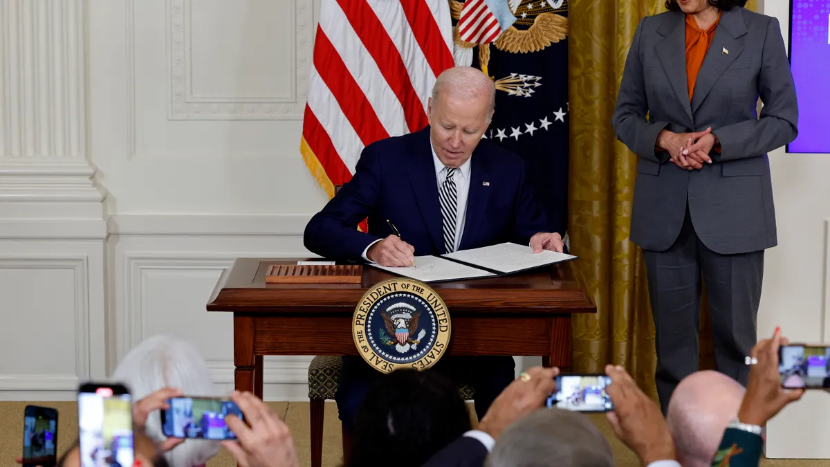 U.S. Vice President Kamala Harris looks on as President Joe Biden signs an executive order.