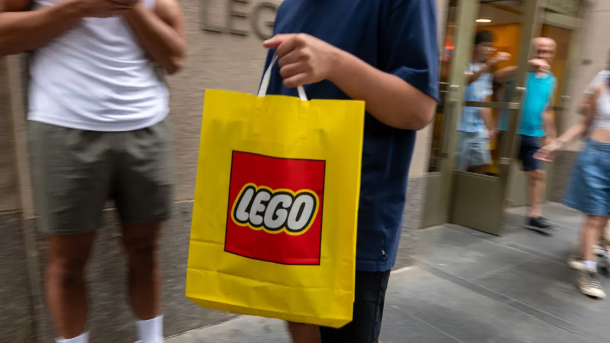 Person carries yellow bag with Lego logo.