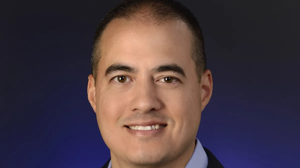 An image of a person in a blue suit smiling.