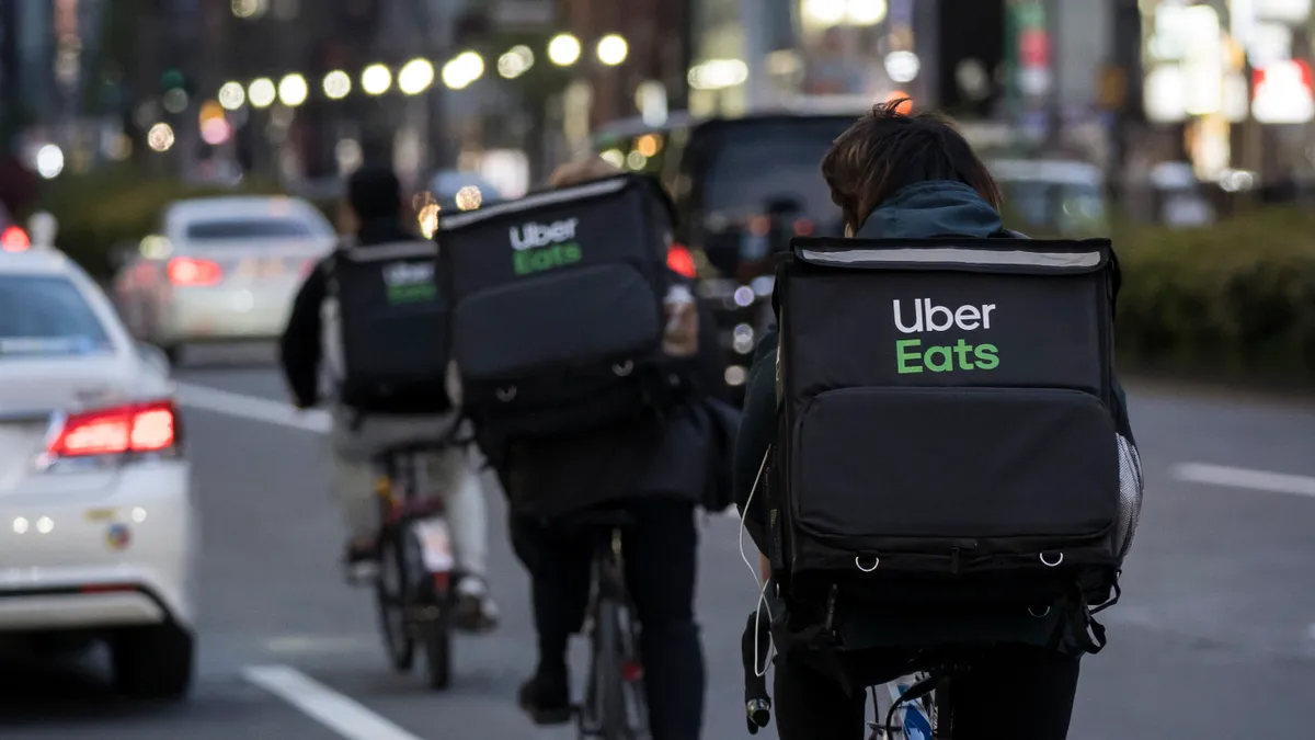 Backs of bike couriers with Uber Eats bags.