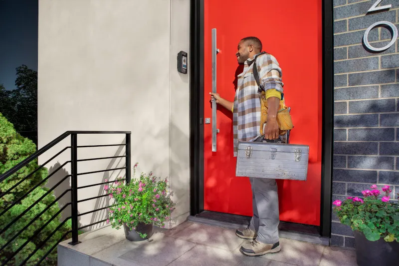 A person uses a smart video intercom while holding a door handle.