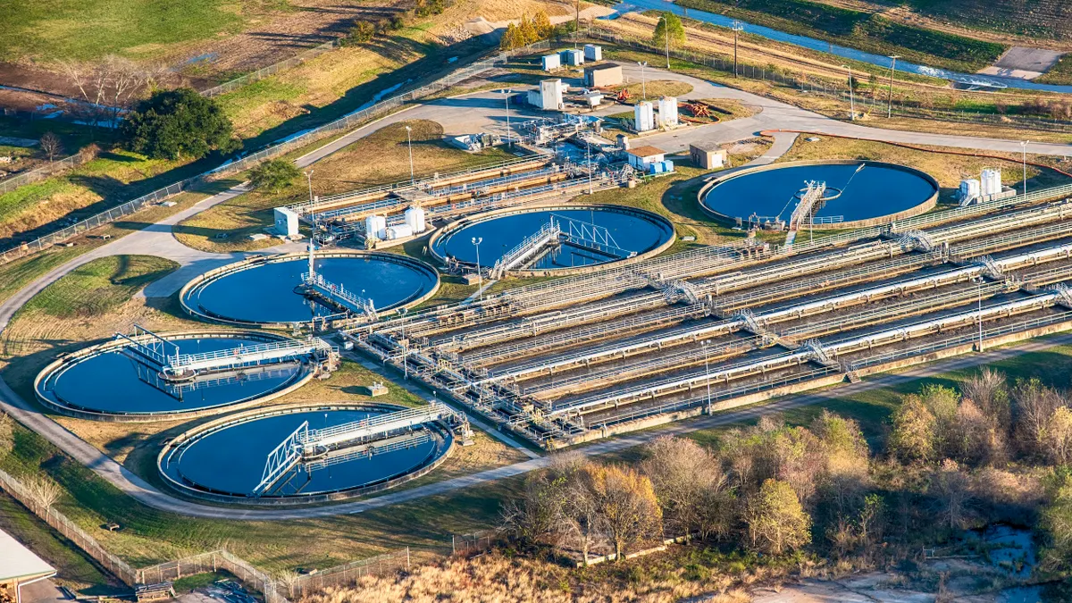 Aerial view of a water treatment plant with 5 large circular pools of blue water and rows of pipes.