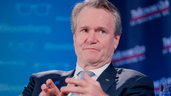 Bank of America CEO Brian Moynihan speaks during an event at the Economic Club, with a blue background behind him.