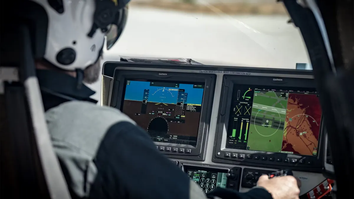 Pilot wearing a helmet looking at digital displays from inside an aircraft.