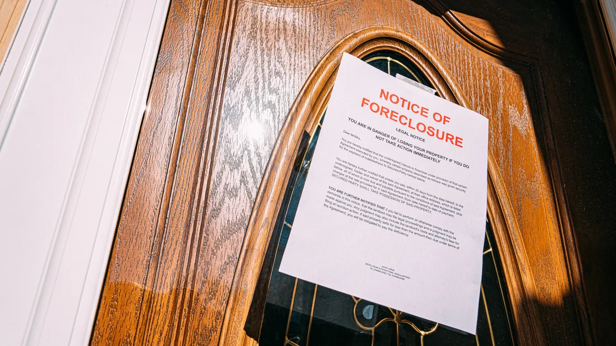 Paper foreclosure notice taped to the glass front door of a home