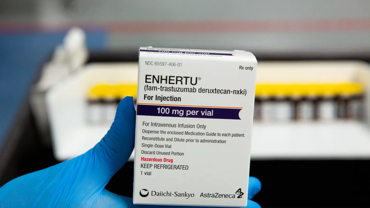 A person wearing blue gloves holds a box of AstraZeneca and Daiichi Sankyo's cancer drug Enhertu