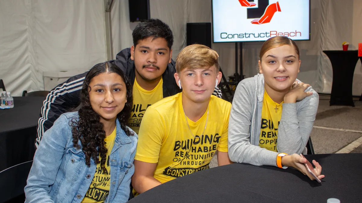 Four students sit at a table wearing bright clothing.