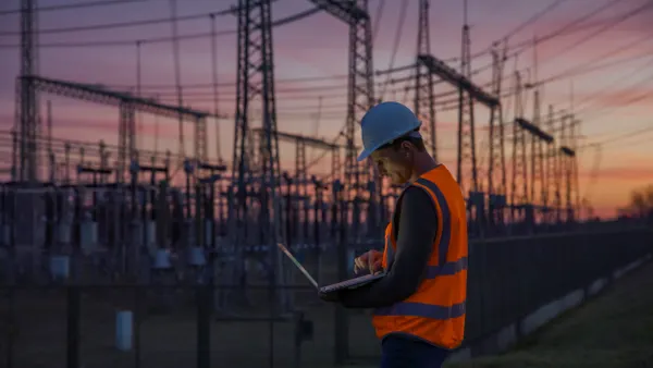 An electrical engineer using a laptop while working at a substation.