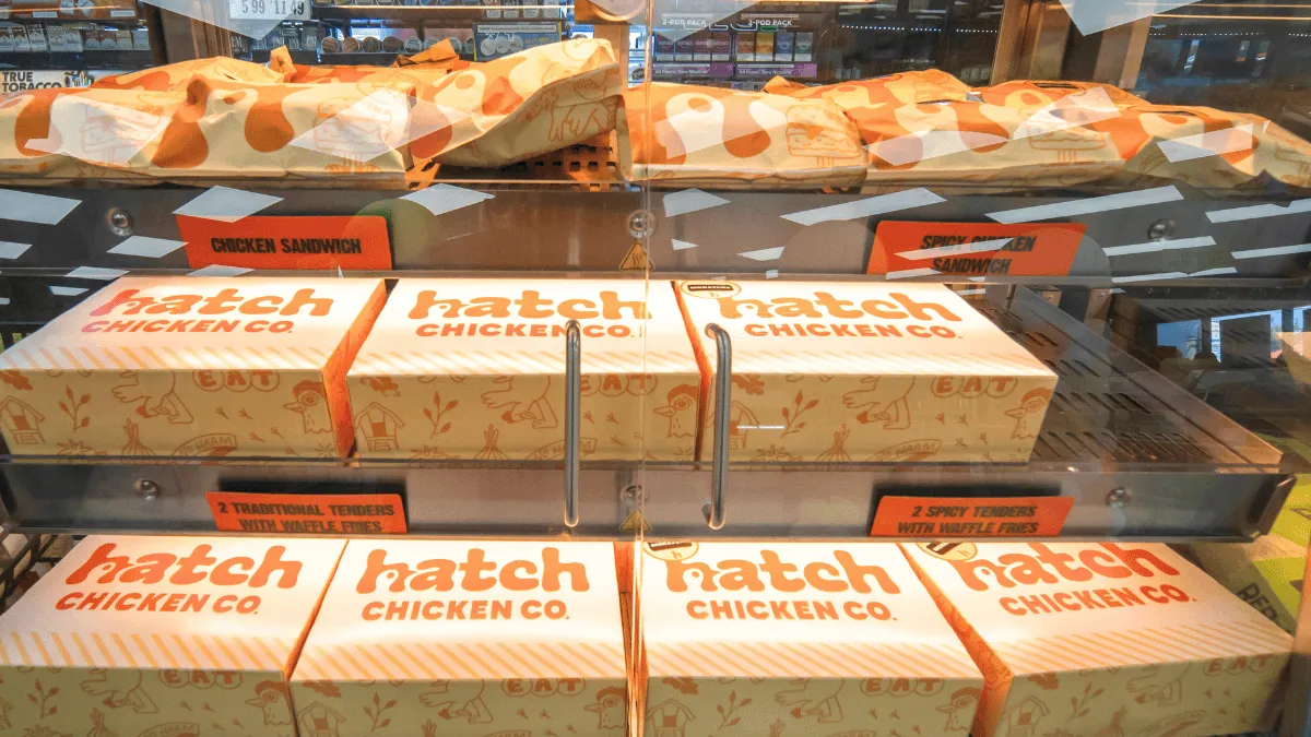 A photo of food items in a warming case in either wrappers or boxes. The boxes read "Hatch chicken."