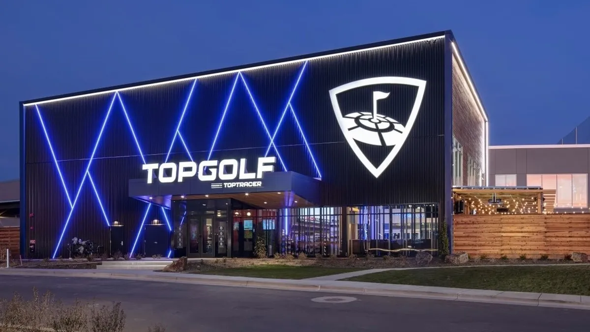 An evening photo of Topfgolf with backlit lights and a white sign that says Topgolf.