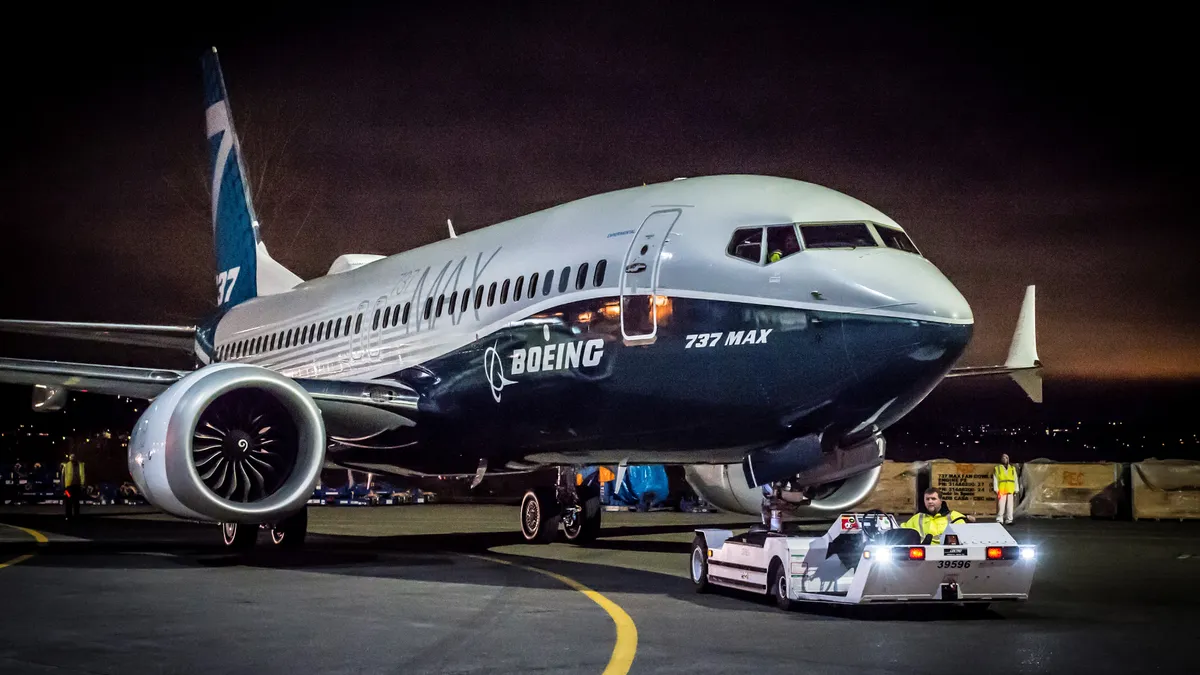 A parked silver and dark blue plane with the white Boeing logo on the front.