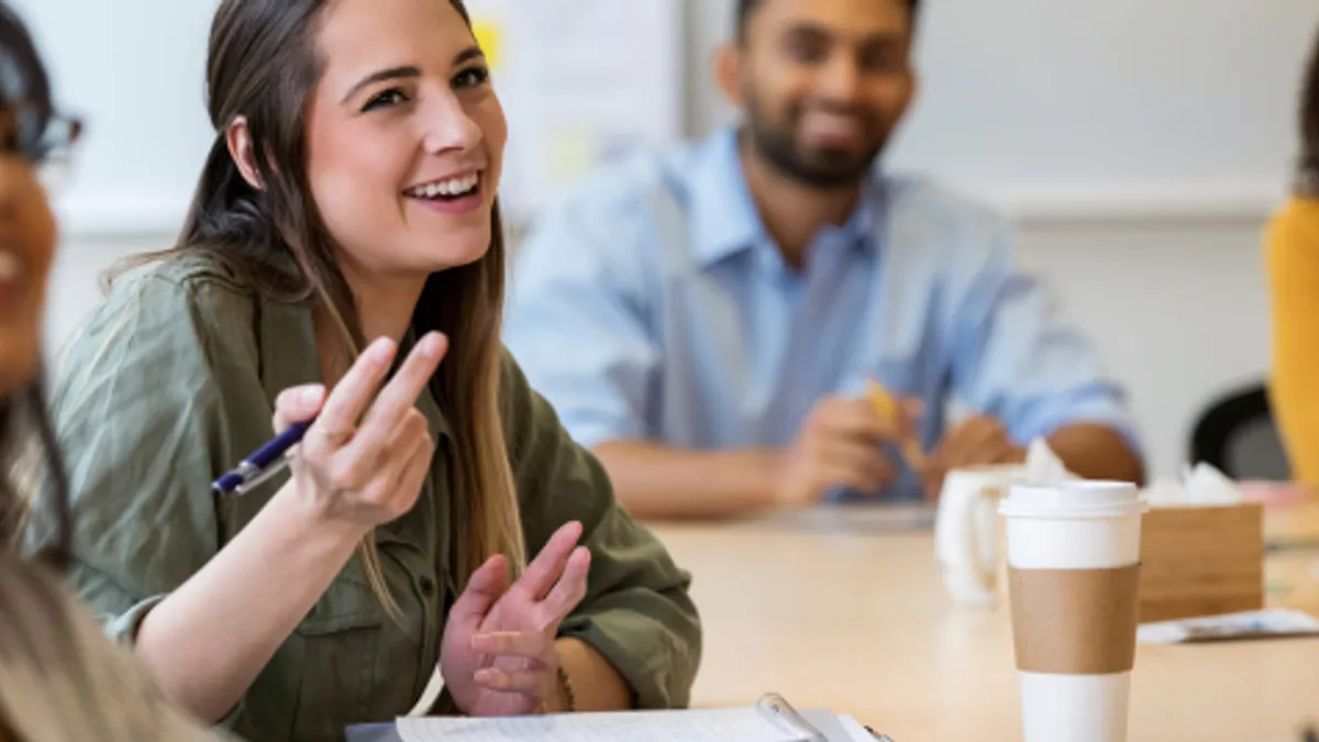 College students sitting at a table smiling and collaborating