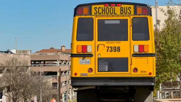 A rear view of a yellow school bus at the top of a hill with a Texas license plate.