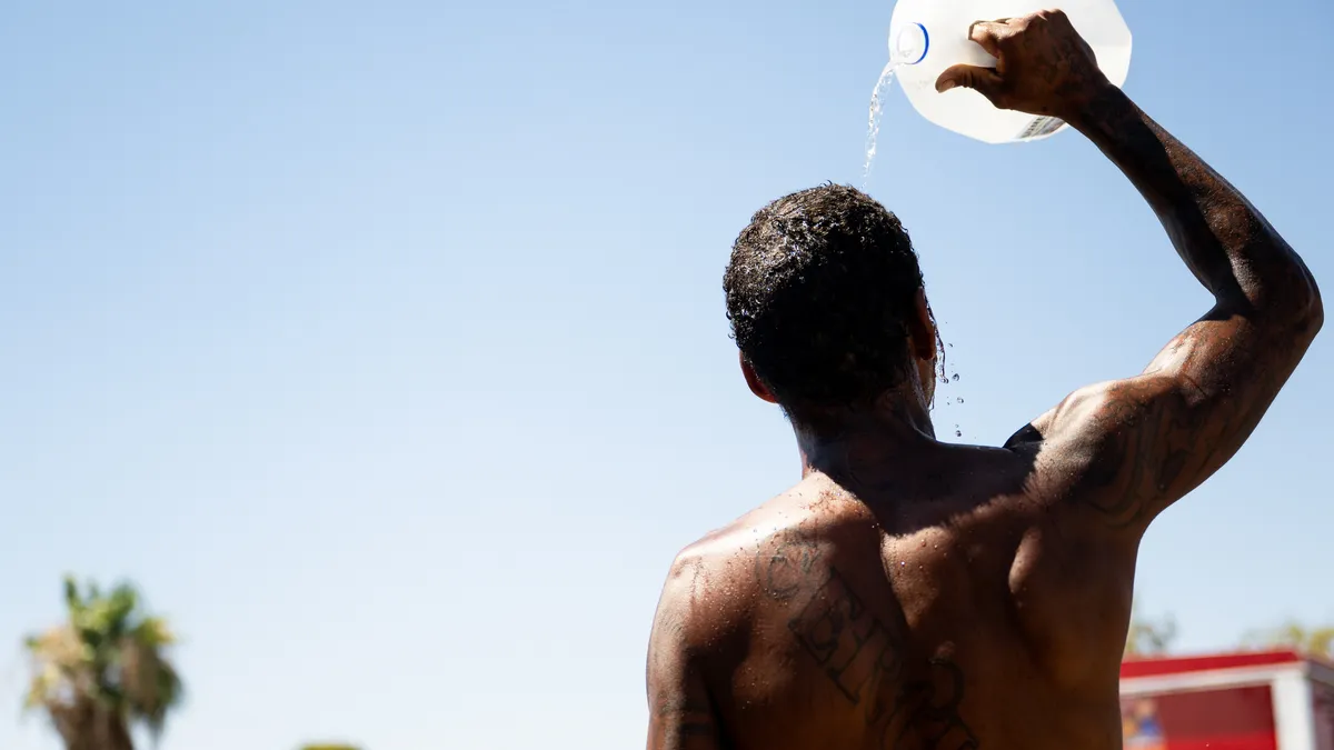 Silhouette of a person pouring a jug of water on themselves