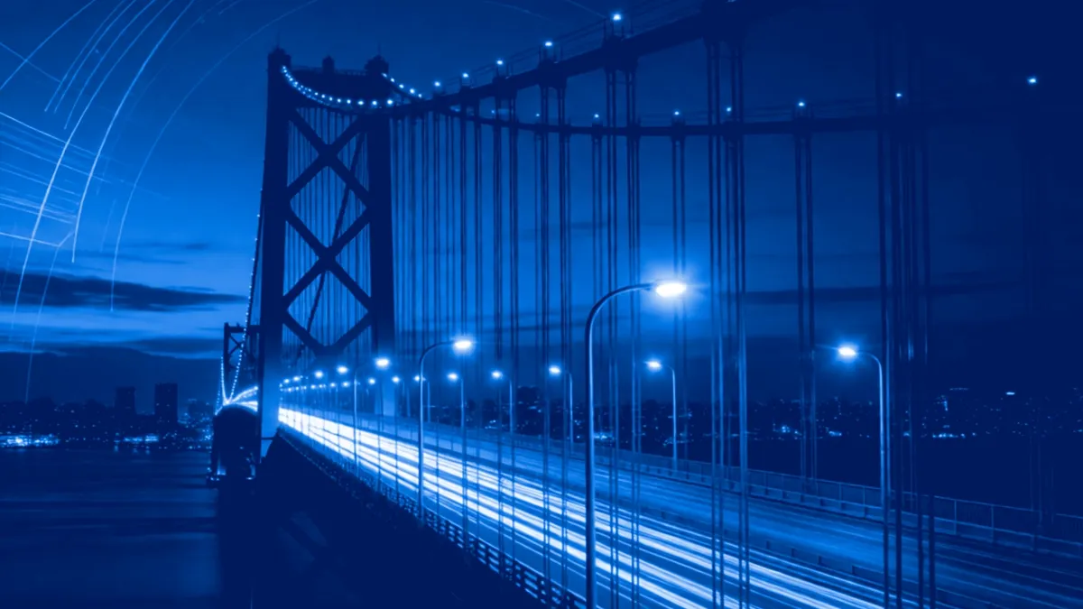 Illuminated suspension bridge at night with light trails.
