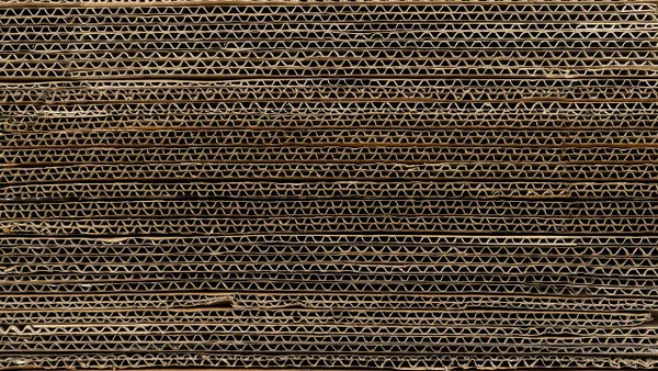 Stacked layers of corrugated cardboard presented in a close-up view, emphasizing the textured zigzag pattern.