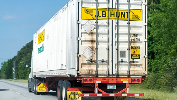 A J.B. Hunt tractor-trailer on a highway with a blue sky and wispy clouds in the background.