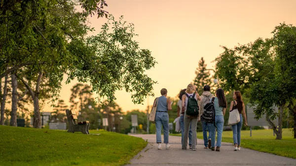 A group of college students walking on a campus pathway.