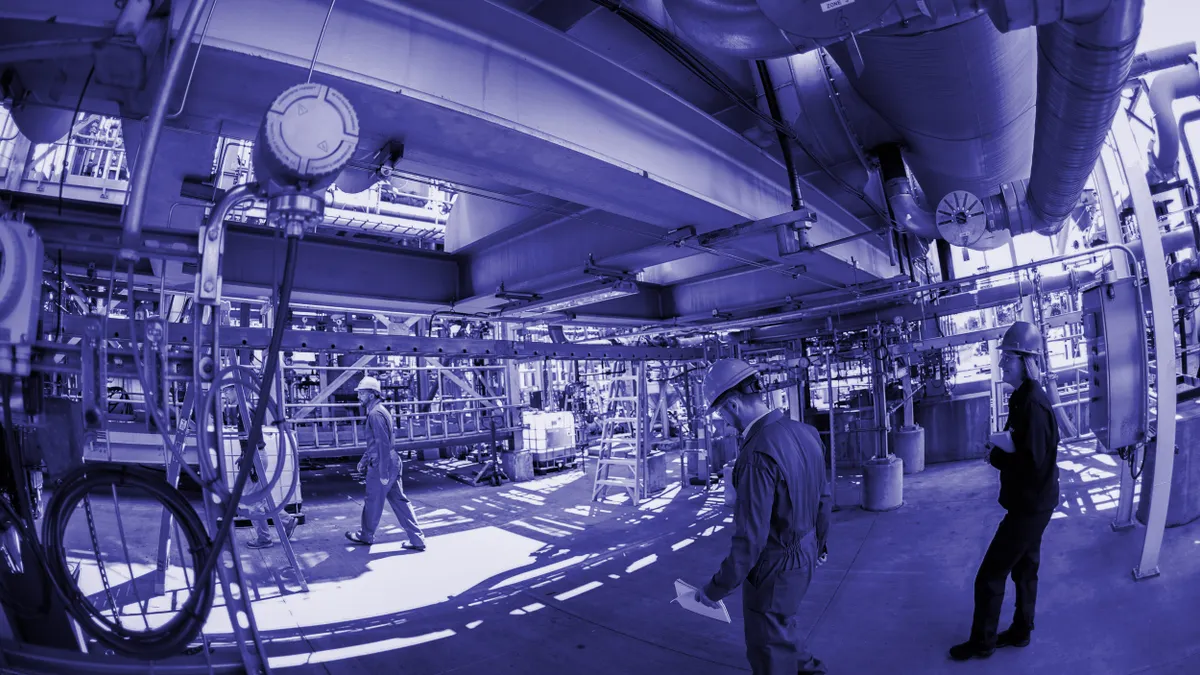 Workers in hardhats walk through a chemical recycling facility.