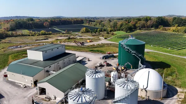 Aerial view of a large facility with multiple large tanks next to an agricultural field.