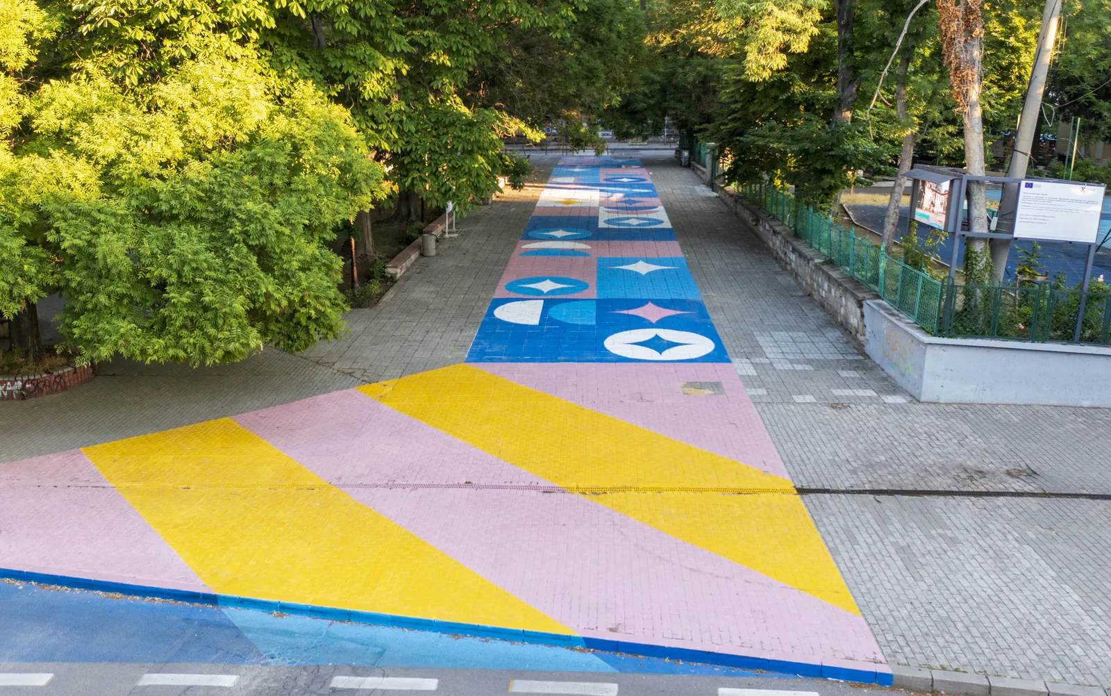 Brightly colored asphalt art on tree-lined path