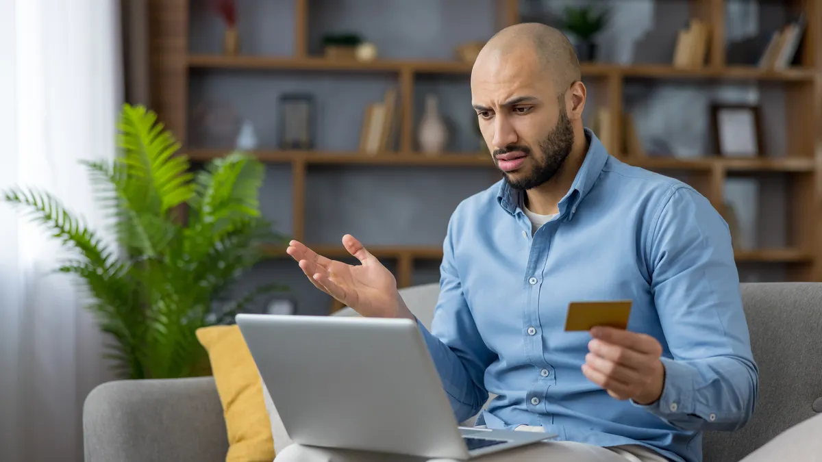 Man looking confused at computer with credit card