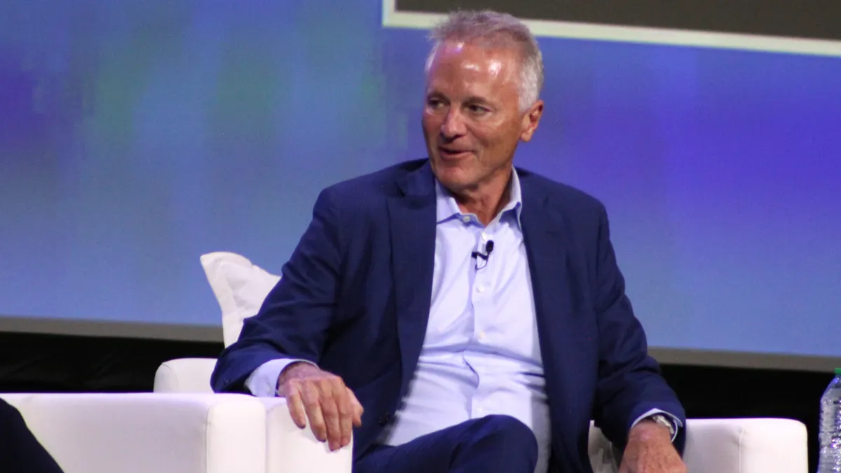 A person wearing a suit sits in a white chair.