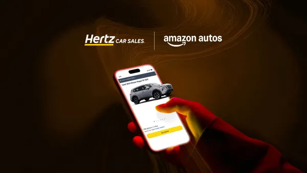 A hand holding a smartphone that shows the Amazon Autos app and the corporate logos of for Hertz Cars Sals and Amazon Autos.