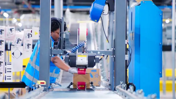 A person places their hand on a package moving along a conveyor belt.