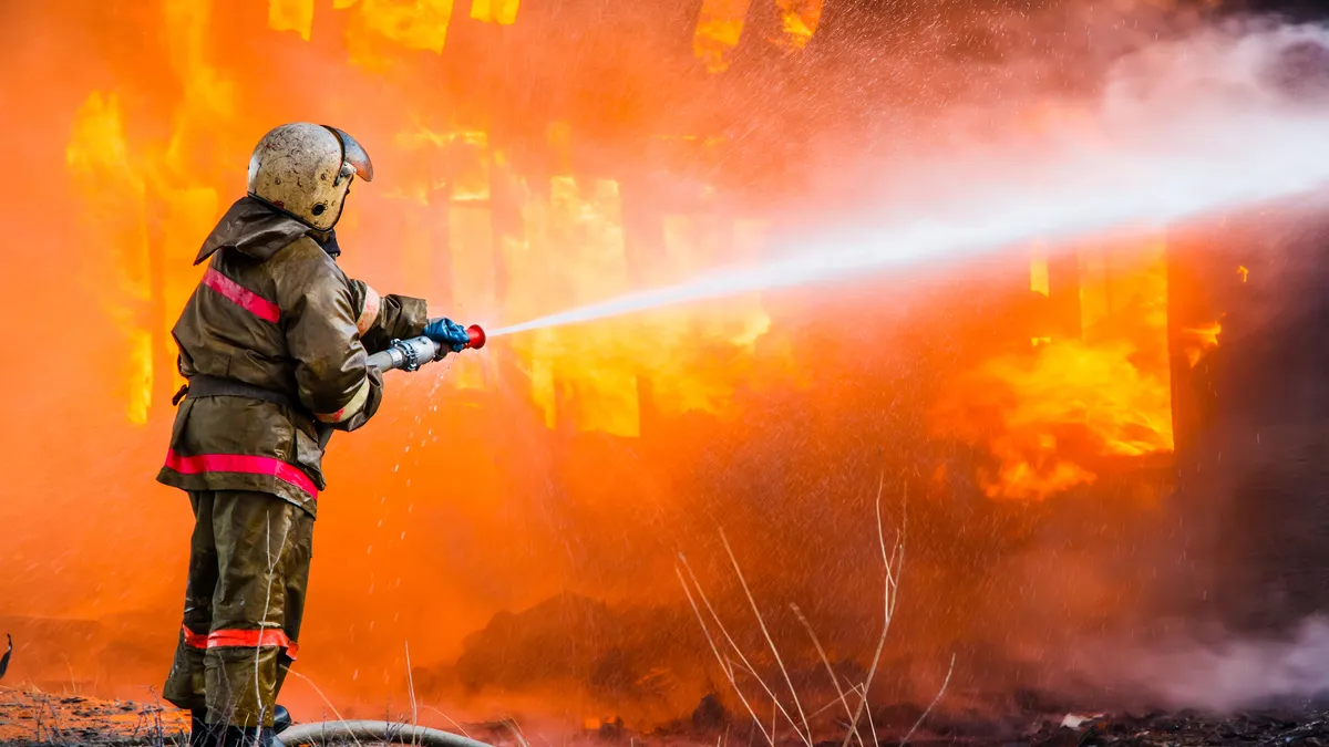 A firefighter sprays a burning building with a hose.