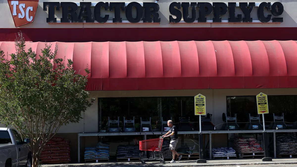 A customer pushes a shopping cart in front of a Tractor Supply Co.