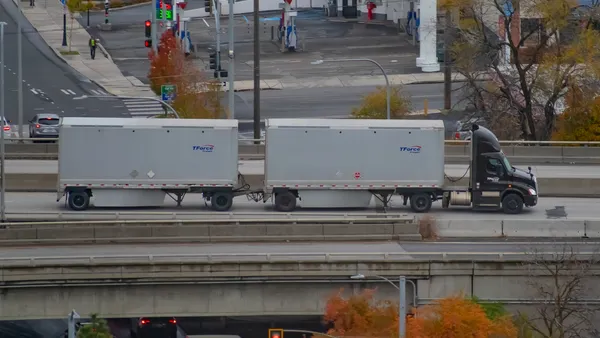 A TForce Freight tractor with a double-combination trailer setup driving on a raised interstate in the city of Spokane, Washington.