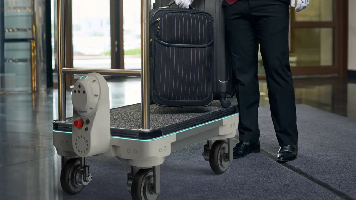 A robot next to a traditional luggage cart.