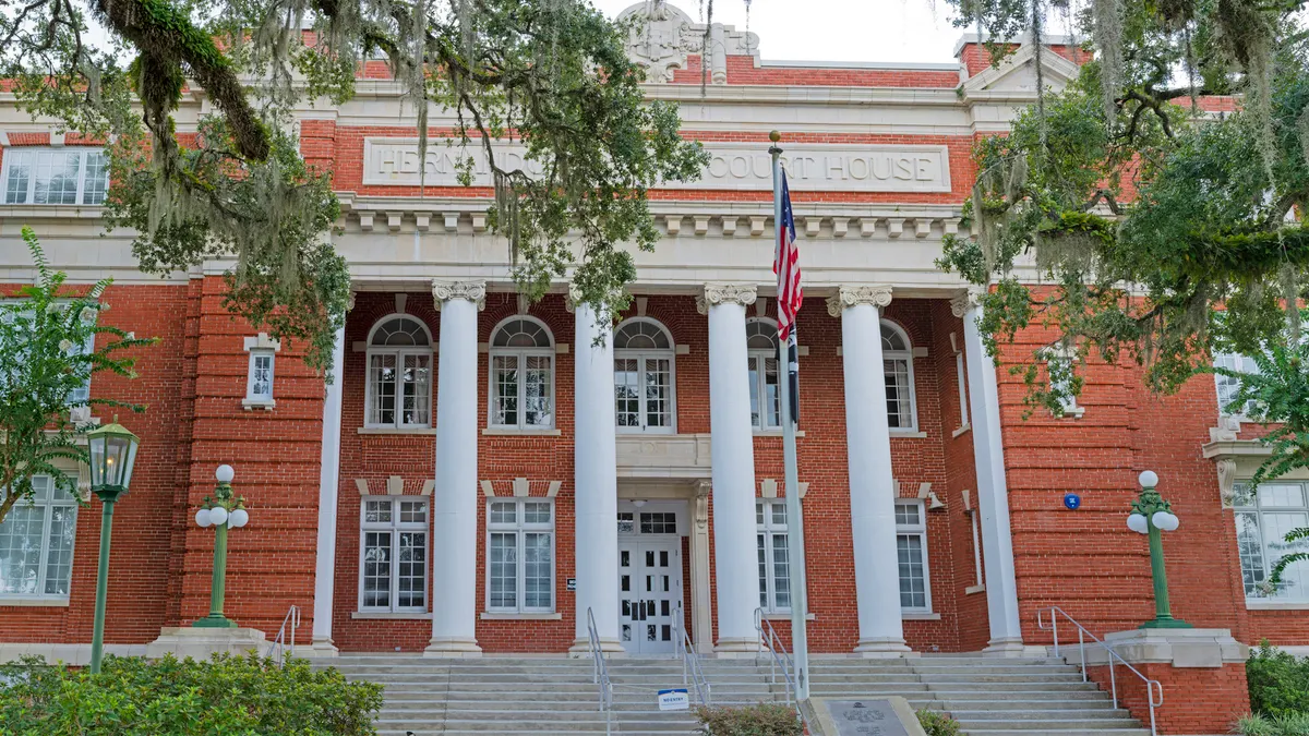 The front of a large brick courthouse building in the Beaux-Arts architectural style