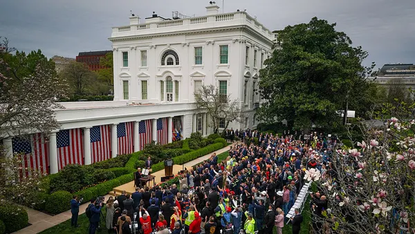 A crowd watches the president sign an executive order in the Rose Garden of the White House.