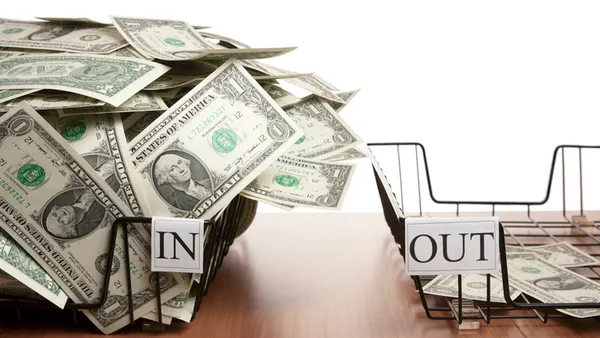 In tray overflowing with dollar notes and empty out tray