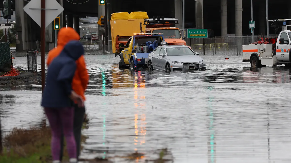 People look on as a tow truck pulls a car out of a flooded intersection on January 04, 2023 in Mill Valley, California.