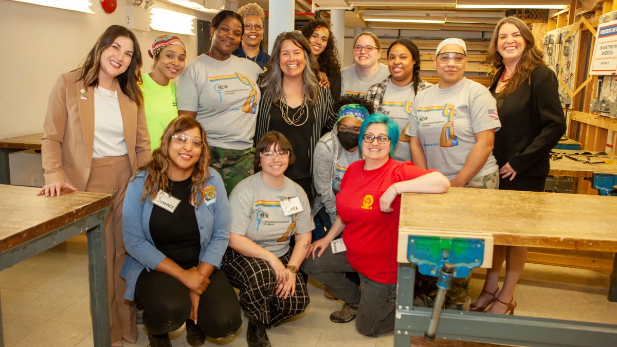 A group of women pose for a photo in a carpentry workshop.