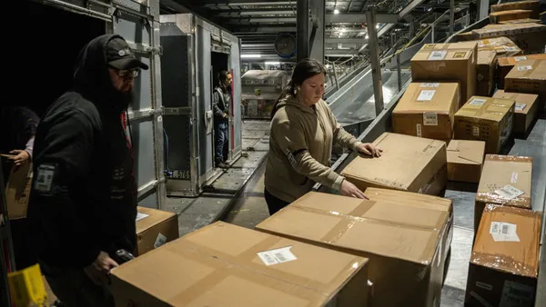 UPS employees load boxes from a posi-sorter chute into an air container at UPS Worldport on January 3, 2022 in Louisville, Kentucky.