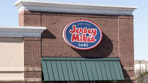 A photogrpah of a building with a brick facade. It has a round sign with blue background and red typeface that says Jersey Mike's Subs