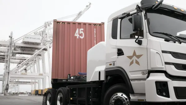A white freight trucks with a red-tan container.